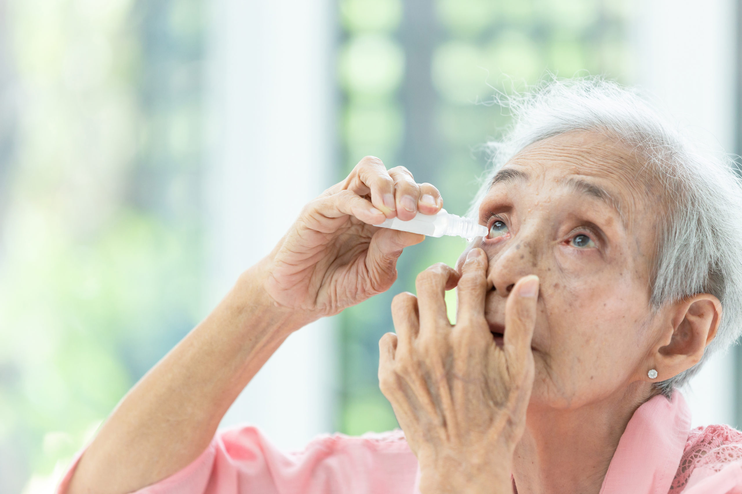 Asian senior woman putting eye drop,closeup view of elderly pers