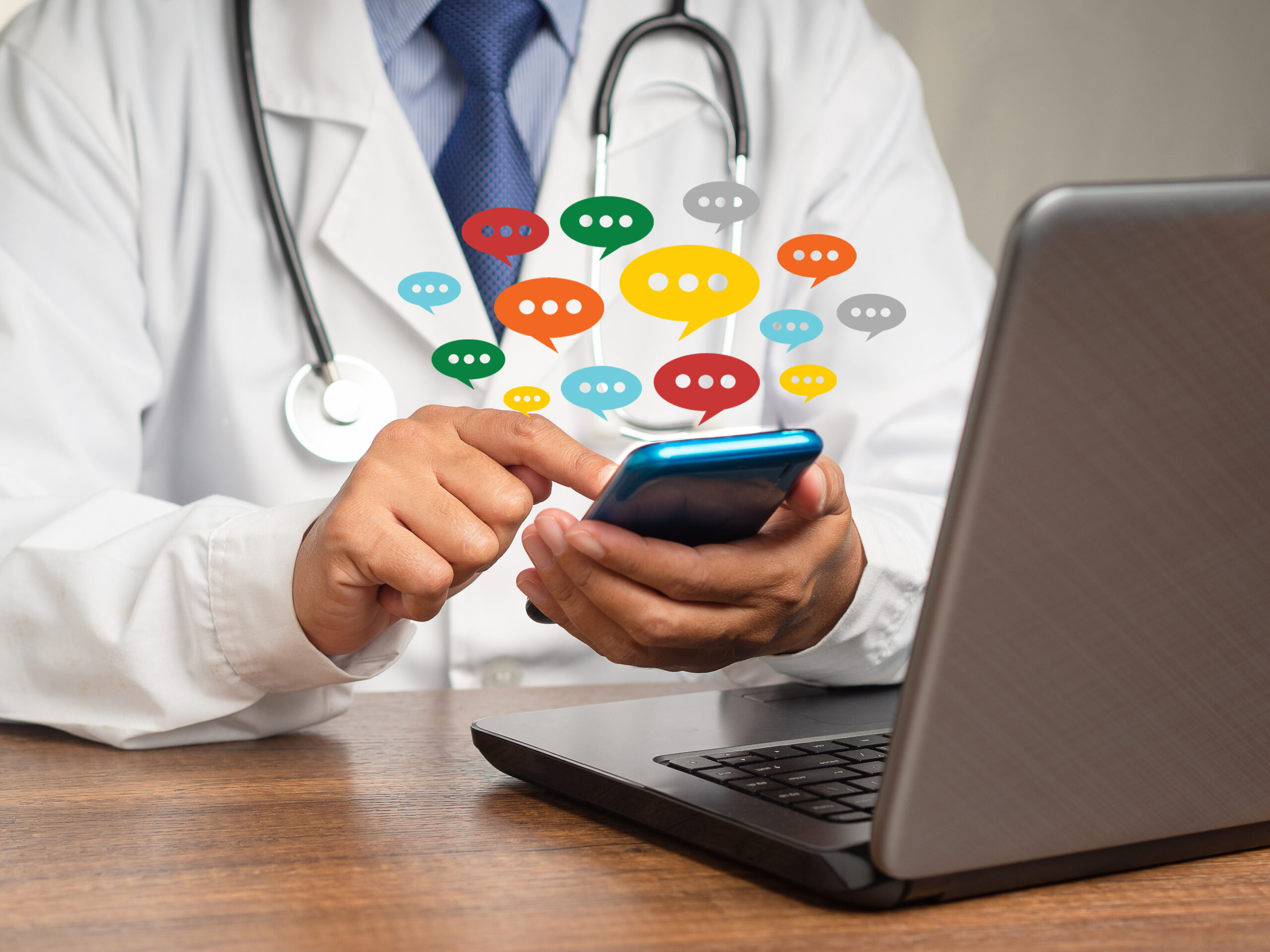 Doctor in a uniform using a smartphone with colorful chat icons