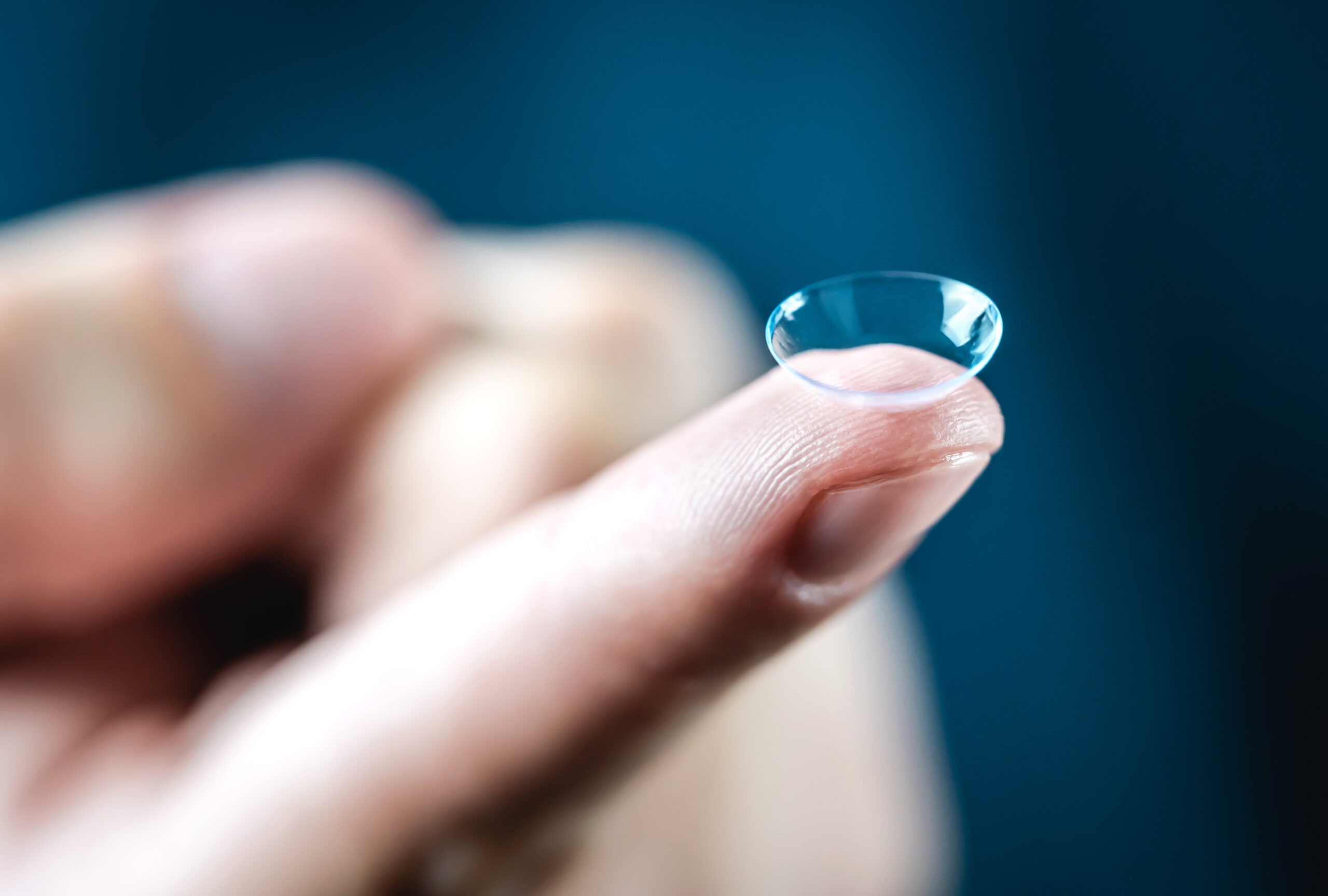 Contact lenses macro close up. Man holding lens on finger. Custo