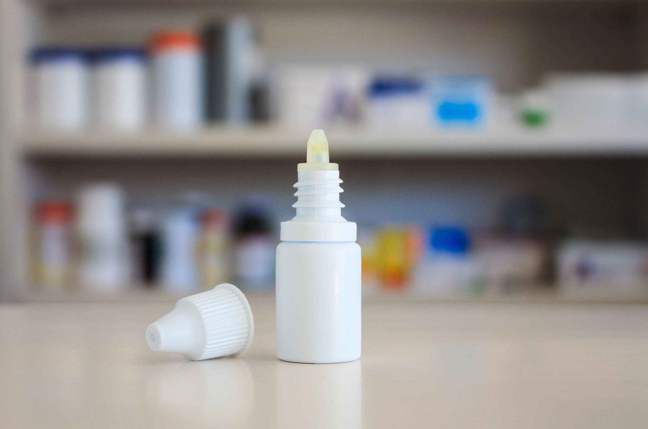 eye ear drops medicine bottle with pharmacy store shelves backgr